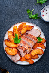 Baked pork tenderloin with sweet quince or apple slices served on white plate. Black table background, top view