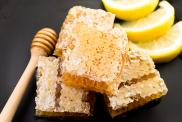 honeycomb and honey with fresh lemon on black background