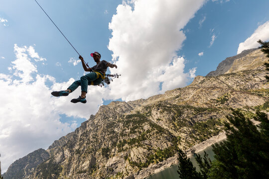 Person climbing in high mountains with yellow jacket rope and helmet in nature, confidence and risk, safety