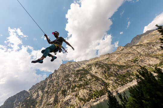 Person climbing in high mountains with yellow jacket rope and helmet in nature, confidence and risk, safety