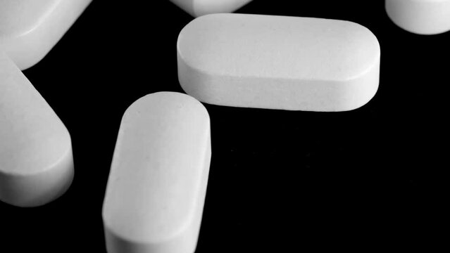 White oblong pills tracking shot close-up. Dependence and drug addiction. Dosage, and prescription refill. Vitamins, antipyretics and antidepressants. 
