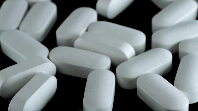 White oblong pills tracking shot close-up, drug testing and medical research. Pharmaceutical industry and medicines.