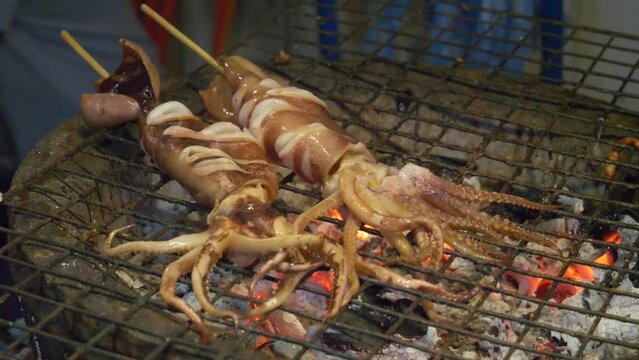 squid in bamboo sticks grill cooked on hot charcoal thailand night market street food booth