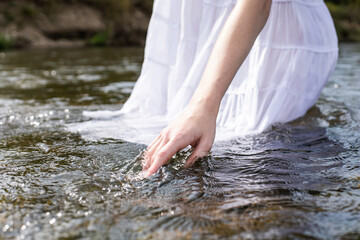 Hand in water. Tenderness. White dress. A gentle female hand touches the water. Vacation.