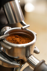 Close-up of freshly ground coffee beans in a portafilter by the coffee grinder