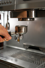 Stainless steel portafilter with ground coffee. Espresso machine parts. Coffee machine in coffee shop.