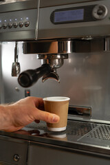Professional barista prepares takeaway coffee in a coffee machine. Favorite job in the restaurant industry.