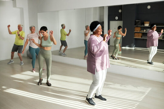 Group of elderly people dancing in health club together with coach