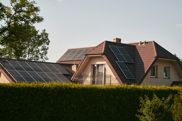 Modern black cells solar panels on the roof of private house. Photovoltaic dotation from European parliament government concept. Renewable energy for the home concept. Sustainable living future.