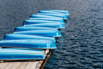 湖畔の桟橋に並べられた手漕ぎボート - obrazy, fototapety, plakaty
