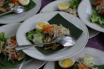 Gado-gado is a typical Indonesian food containing boiled vegetables, sliced eggs and tofu, sprinkled with fried onions and crackers and served with peanut sauce.