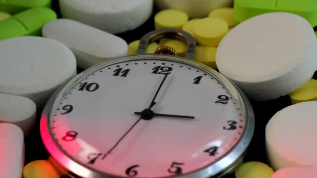 Background of multi-colored pills, tablets and watch. Medicines that prolong life and cause drug addiction. Importance of providing medical care on tim