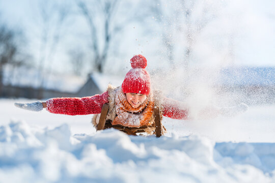 Funny little child runs on sledge in snow. Active sports games in winter time. Happy winter holidays concept. - Powered by Adobe