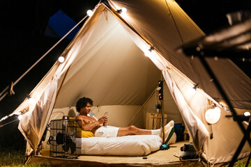 latin man talking sending a message on the smartphone on a tent