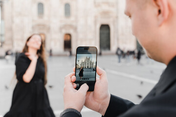 A couple in love take a photo on a smartphone in Duomo square, Milan