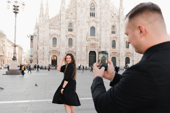 A couple in love take a photo on a smartphone in Duomo square, Milan