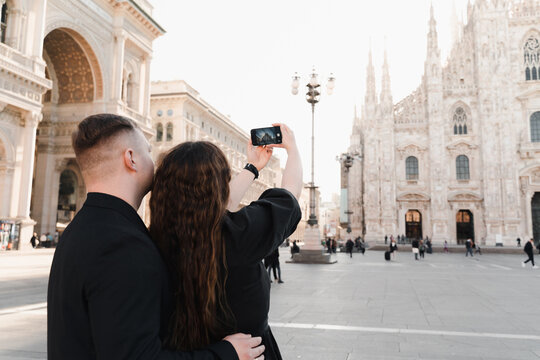 A couple in love take a photo on a smartphone in Duomo square, Milan