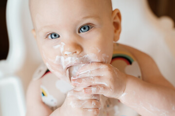 Cute grubby six month old baby eating yogurt by himself