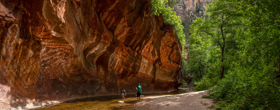 Young couple enjoy the sun in a stream under rock ledge