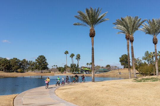 A family rides bikes next to lake in desert park