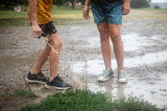 Kids splashing in mud puddle in the rain