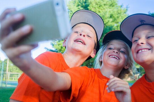 A 10 year old girl on the baseball team takes selfies with teammates