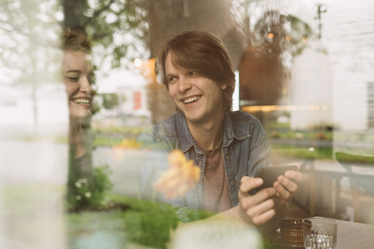 Cheerful young couple sitting with smartphone at table