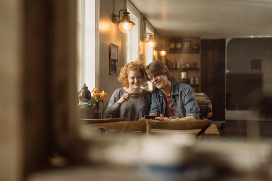 Happy young couple sitting with smartphone at table