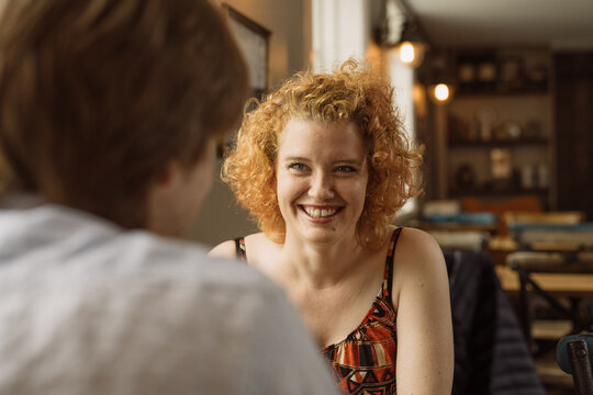 Cheerful young woman with a friend sitting at table in cafe