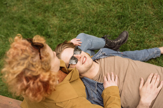 Happy couple relaxing on grass in park on sunny day