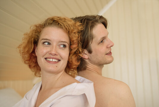 Cheerful young couple leaning on each other in room with daylight