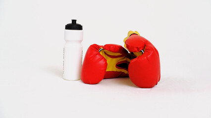 Sports drinks and sports equipment. Boxing gloves and a sports protein bottle on a white background.