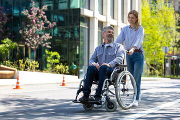Man in wheelchair and woman walking in city street.