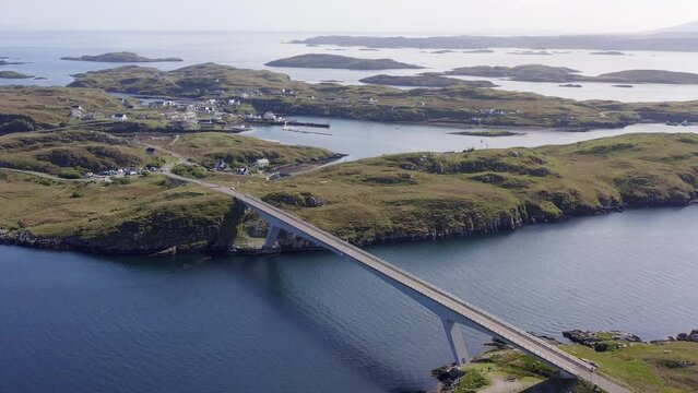 Retreating drone shot of the bridge connecting Scalpay to the Isle of Harris, part of the Outer Hebrides of Scotland. The Minch sea is visible as well as many cliffs and mountains.