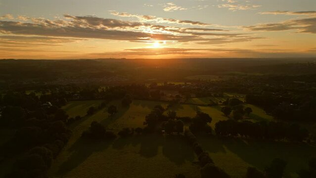 Establishing Drone Shot into the Sun Over Grass Fields at Golden Hour Sunrise