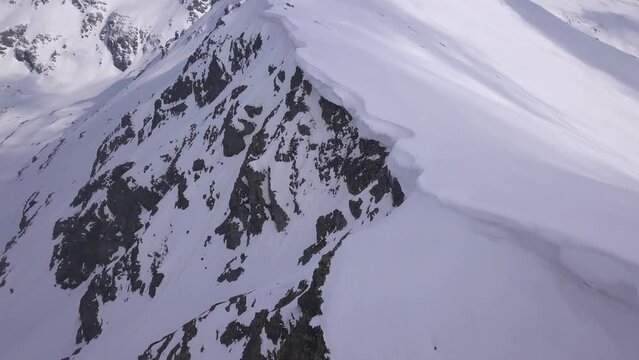 Rugged mountain snowy landscape view from drone. Cornice of snow hanging over ridge high in Parang Mountains of Romania.