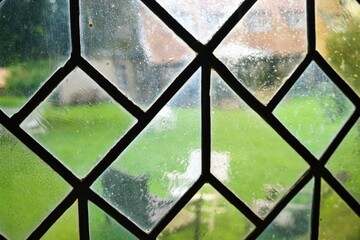 Kirchenfenster vor Gartenwiese mit schwarzen und weißen Stühlen 