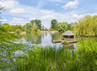 Obraz premium Wooden house for birds on the water. Beautiful Lake Dovesee with sky reflection in the water in Braunschweig Leisure Park. Spring landscape. Ecology, environmental protection.