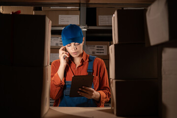 Warehouse manager conversation over mobile phone while tracking supply order details using digital...