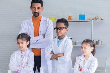 Fototapeta na wymiar Hispanic or Indian teacher wearing lab coat and multicultural students holding magnifier glasses looking at camera in laboratory science class, lifestyle modern education in lab for students concept
