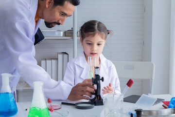 Hispanic or Indian teacher wearing lab coat concentrate on elementary students girl kid using microscope in laboratory science class, lifestyle modern education at school for elementary pupil concept