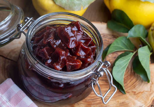 Homemade quince jam in a glass jar on an old wooden background. Fresh quince fruits and leaves and quince jam. (Turkish name; ayva receli)