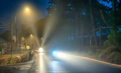 Fototapeta na wymiar Da Lat, Vietnam - April 11th, 2023: The night scene on the suburban street when the city is covered in fog with street lights is so peaceful