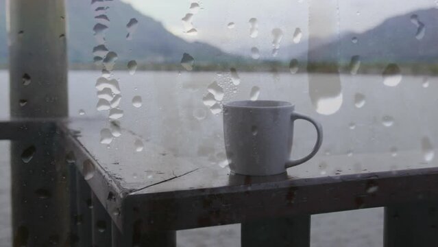 Animation of rain drops over window, cup of coffee lake and landscape