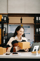 Beautiful Asian lady blogger showing clothes in front of the camera to recording vlog video live streaming at her shop. Online Shopping\