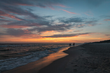 Para spaceruje na plaży o wschodzie słońca.