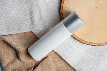 Plastic white tube for cream or lotion. Skin care or sunscreen cosmetic on brown cloth background.