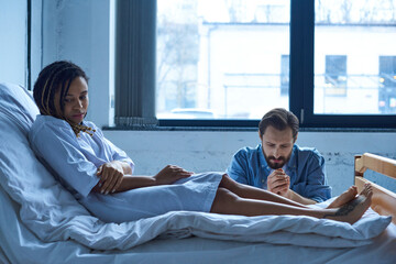 miscarriage concept, man grieving near depressed african american woman, hospital, private ward