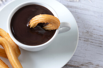 Traditional Spanish churros with hot chocolate breakfast on wooden table