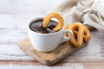 Traditional Spanish churros with hot chocolate breakfast on wooden table